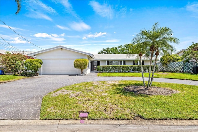 ranch-style house with a garage, a front yard, fence, and curved driveway