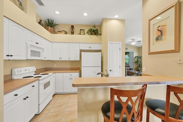 121 Auburn Woods Cir, Venice, FL 34292 - kitchen with a breakfast bar area, a peninsula, light tile patterned floors, white appliances, and ceiling fan
