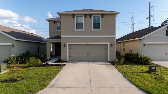 traditional-style home with concrete driveway, a front yard, and stucco siding