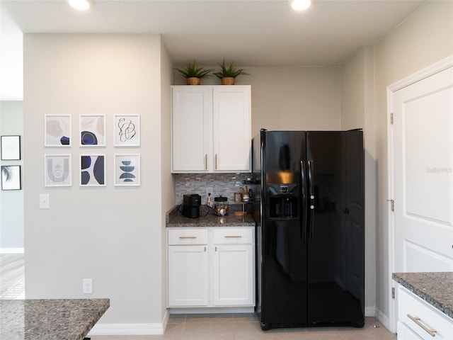 4907 Wedgeleaf Way, Palmetto, FL 34221 - kitchen with decorative backsplash, baseboards, dark stone counters, black fridge, and white cabinetry