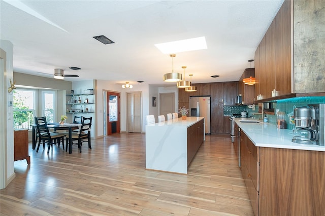 23 Tiffany St, Englewood, FL 34223 - kitchen with stainless steel refrigerator with ice dispenser, a skylight, light countertops, and a center island