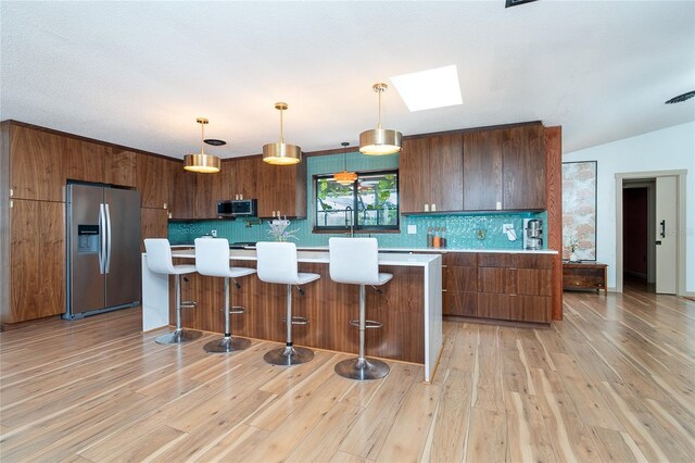 23 Tiffany St, Englewood, FL 34223 - kitchen with appliances with stainless steel finishes, light countertops, a skylight, backsplash, and light wood-type flooring