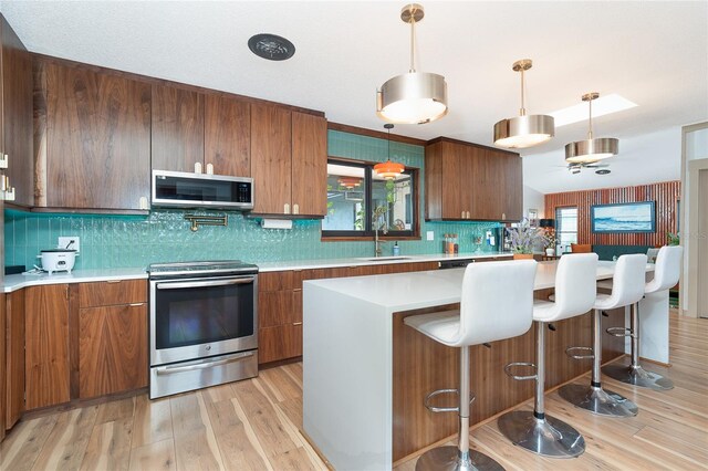 23 Tiffany St, Englewood, FL 34223 - kitchen featuring stainless steel appliances, a sink, light countertops, tasteful backsplash, and light wood-type flooring