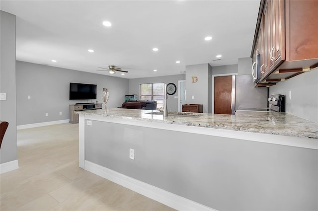 4068 Palau Dr, Sarasota, FL 34241 - kitchen featuring range, a peninsula, light stone counters, a ceiling fan, and recessed lighting