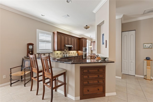 1625 Lancashire Dr, Venice, FL 34293 - kitchen featuring light tile patterned floors, a peninsula, under cabinet range hood, crown molding, and dark stone counters