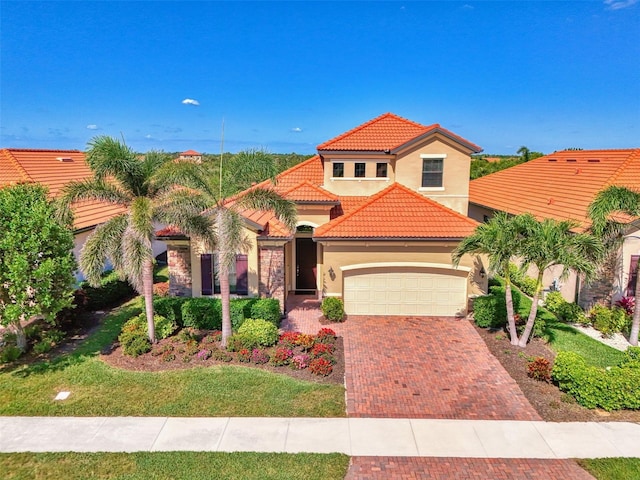 24193 Gallberry Dr, Venice, FL 34293 - mediterranean / spanish house with stucco siding, decorative driveway, an attached garage, and a tile roof