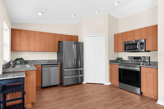 511 Porpoise Rd, Venice, FL 34293 - kitchen with light wood finished floors, stainless steel appliances, vaulted ceiling, a sink, and dark stone counters