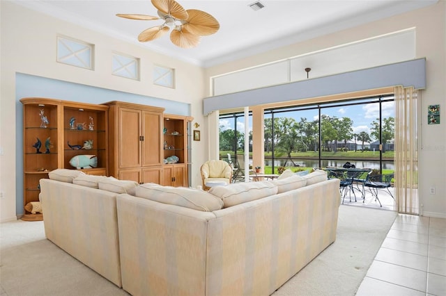 living area with crown molding, light tile patterned floors, a ceiling fan, visible vents, and baseboards