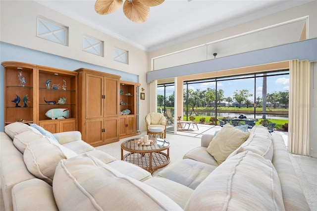 living area featuring a towering ceiling, crown molding, and a ceiling fan