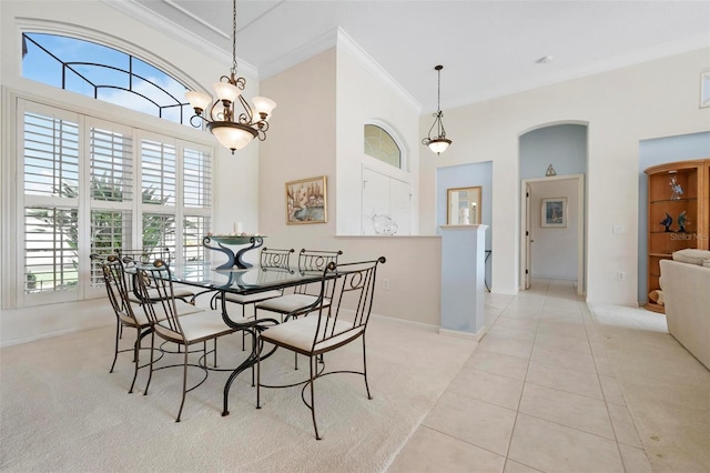 dining room featuring light tile patterned floors, baseboards, arched walkways, a high ceiling, and ornamental molding