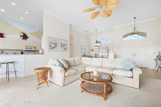 living area featuring crown molding, light tile patterned floors, a towering ceiling, and ceiling fan with notable chandelier
