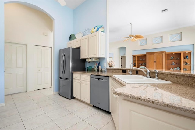 kitchen featuring light tile patterned floors, arched walkways, a ceiling fan, a sink, and stainless steel appliances