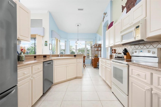 kitchen with light tile patterned floors, light countertops, decorative backsplash, stainless steel appliances, and a sink
