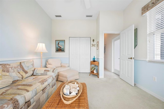 living area with light carpet, visible vents, baseboards, and a ceiling fan