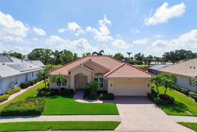 mediterranean / spanish house featuring stucco siding, driveway, a front lawn, an attached garage, and a tiled roof