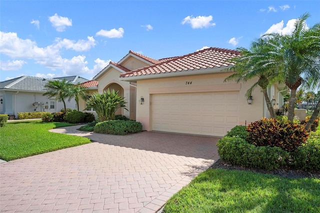 mediterranean / spanish home with stucco siding, decorative driveway, a front lawn, a garage, and a tiled roof