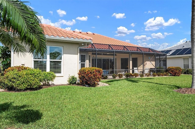 back of property with a yard, a tile roof, a lanai, and stucco siding