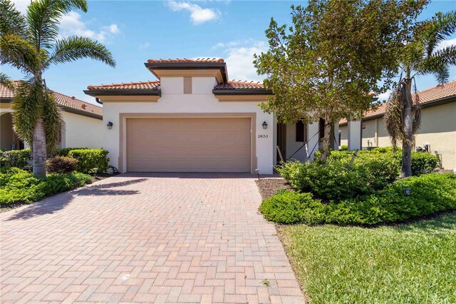 24153 Spartina Dr, Venice, FL 34293 - mediterranean / spanish-style home featuring a garage, stucco siding, decorative driveway, and a tile roof