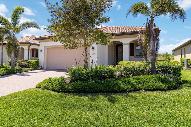 24153 Spartina Dr, Venice, FL 34293 - mediterranean / spanish-style house featuring stucco siding, driveway, a front lawn, a garage, and a tiled roof