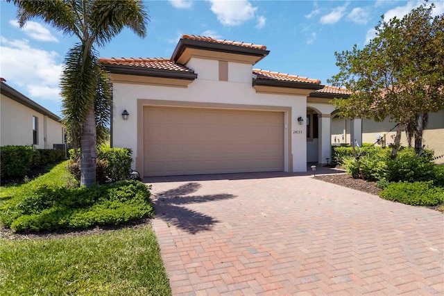 24153 Spartina Dr, Venice, FL 34293 - mediterranean / spanish-style home with a tile roof, a garage, decorative driveway, and stucco siding