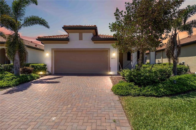 24153 Spartina Dr, Venice, FL 34293 - mediterranean / spanish house with an attached garage, stucco siding, a tile roof, and decorative driveway