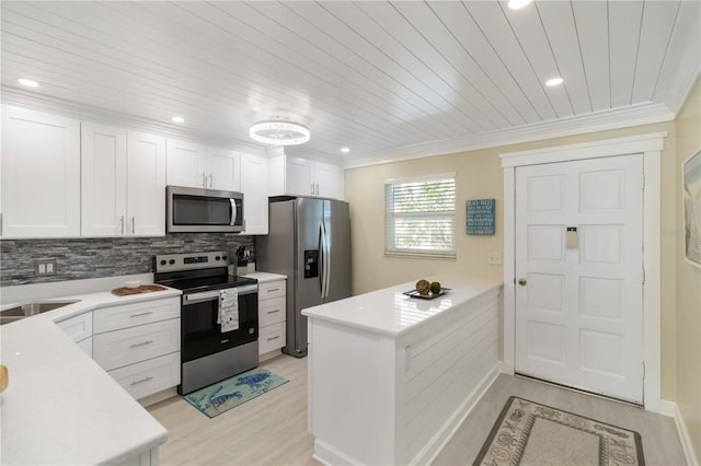 kitchen with a peninsula, light countertops, white cabinets, stainless steel appliances, and light wood finished floors