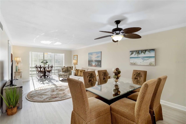 dining space featuring a ceiling fan, wood finished floors, baseboards, and ornamental molding