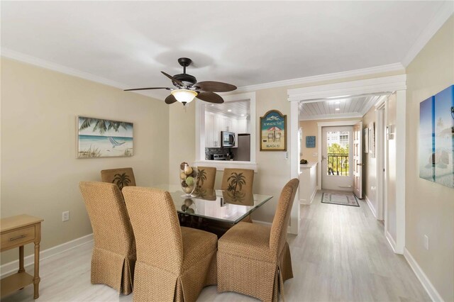dining space featuring light wood-style floors, baseboards, ornamental molding, and a ceiling fan