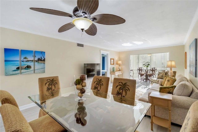 dining area with crown molding, ceiling fan, light wood-style flooring, visible vents, and baseboards