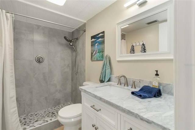 full bathroom with tiled shower, vanity, visible vents, and toilet