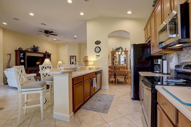 2542 Cortenova Ct, Venice, FL 34292 - kitchen featuring brown cabinets, a breakfast bar area, appliances with stainless steel finishes, arched walkways, and a sink
