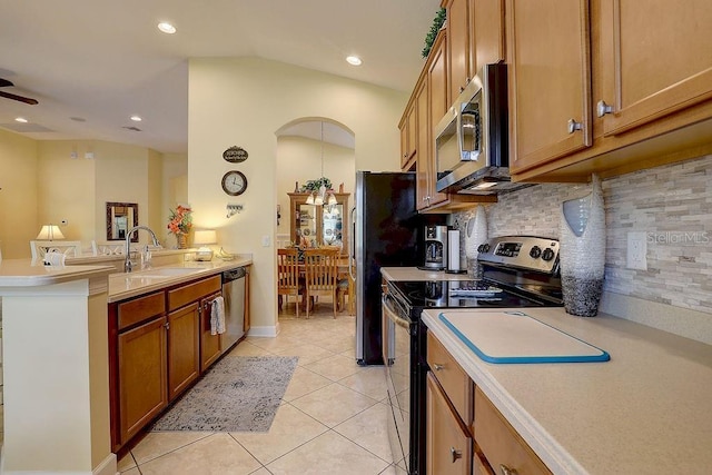 2542 Cortenova Ct, Venice, FL 34292 - kitchen with a peninsula, brown cabinets, appliances with stainless steel finishes, arched walkways, and a sink