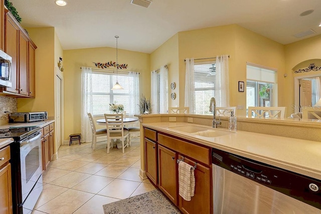2542 Cortenova Ct, Venice, FL 34292 - kitchen featuring stainless steel appliances, brown cabinetry, a sink, and light tile patterned flooring