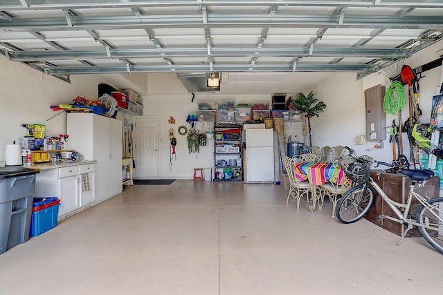 2542 Cortenova Ct, Venice, FL 34292 - garage featuring a garage door opener, freestanding refrigerator, and electric panel