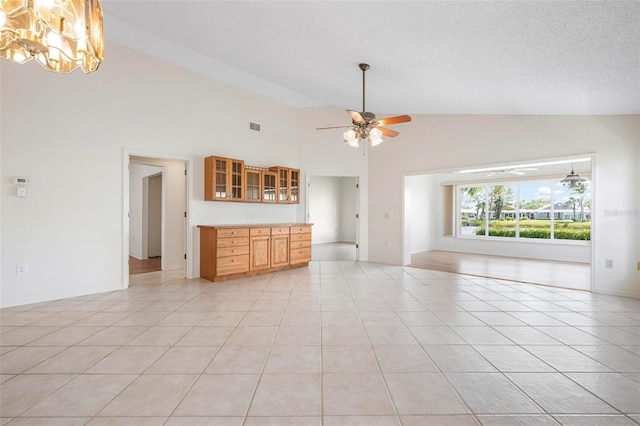 799 Harrington Lake Dr N Unit 73, Venice, FL 34293 - unfurnished living room featuring light tile patterned floors, visible vents, a textured ceiling, ceiling fan with notable chandelier, and high vaulted ceiling