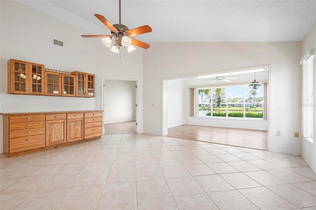799 Harrington Lake Dr N Unit 73, Venice, FL 34293 - unfurnished living room with light tile patterned floors, a textured ceiling, visible vents, ceiling fan, and high vaulted ceiling