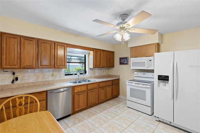 kitchen with brown cabinetry, white appliances, light countertops, and a sink