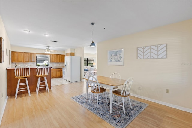dining space featuring visible vents, baseboards, ceiling fan, and light wood-style floors