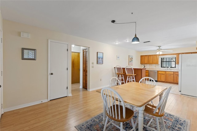 dining space with light wood-type flooring, ceiling fan, baseboards, and visible vents