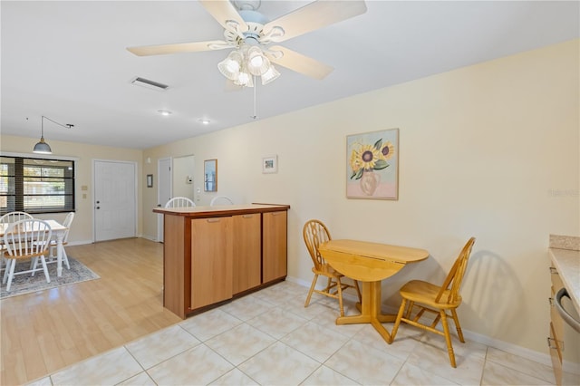 kitchen featuring light wood-style floors, a peninsula, a ceiling fan, visible vents, and baseboards