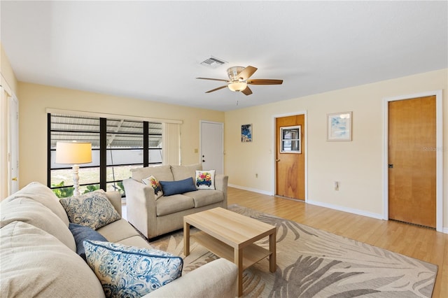 living area with light wood-type flooring, visible vents, baseboards, and ceiling fan