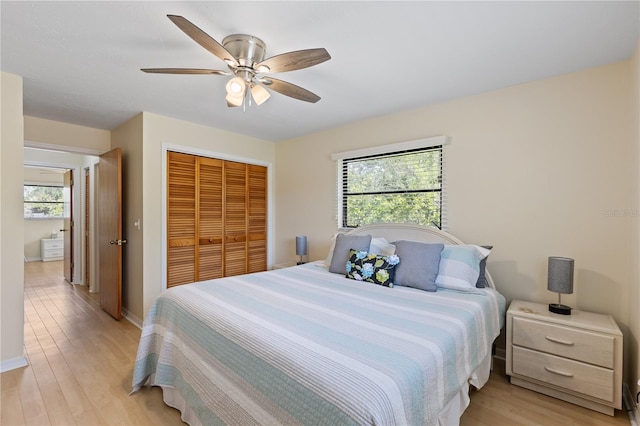 bedroom with light wood-style flooring, a closet, ceiling fan, and baseboards
