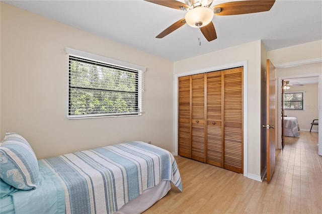 bedroom featuring a closet, light wood-style flooring, a ceiling fan, and baseboards