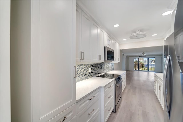 700 Golden Beach Blvd Unit 115, Venice, FL 34285 - kitchen featuring stainless steel appliances, tasteful backsplash, light countertops, light wood-type flooring, and white cabinets