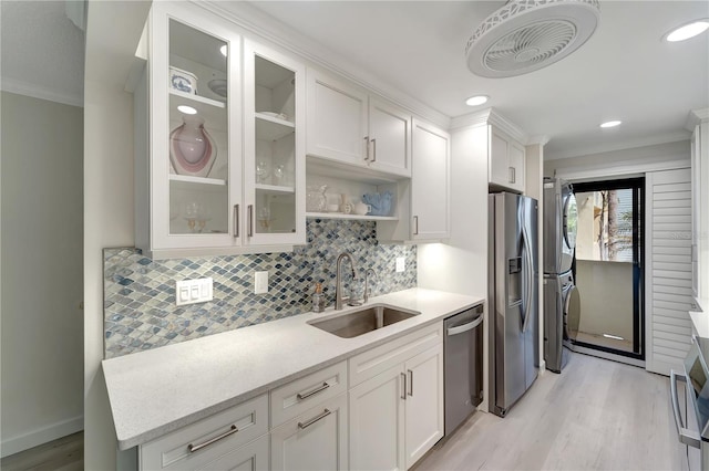 700 Golden Beach Blvd Unit 115, Venice, FL 34285 - kitchen featuring stacked washer / dryer, a sink, appliances with stainless steel finishes, crown molding, and light wood-type flooring