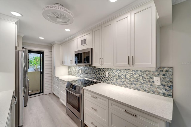 700 Golden Beach Blvd Unit 115, Venice, FL 34285 - kitchen with stainless steel appliances, white cabinetry, light wood-style flooring, backsplash, and recessed lighting