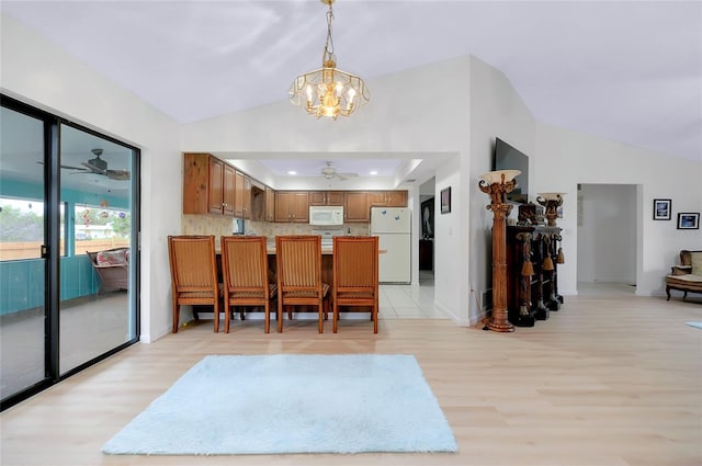 990 Sea Fox Rd, Venice, FL 34293 - kitchen featuring white appliances, a peninsula, brown cabinetry, vaulted ceiling, and ceiling fan with notable chandelier