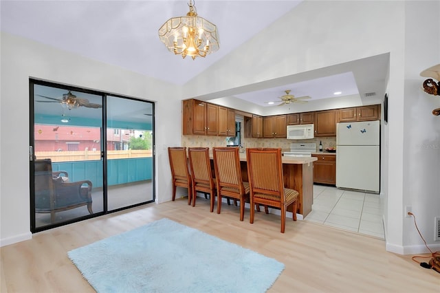 990 Sea Fox Rd, Venice, FL 34293 - kitchen with brown cabinets, ceiling fan with notable chandelier, white appliances, and a peninsula