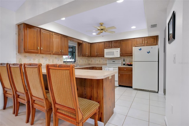 990 Sea Fox Rd, Venice, FL 34293 - kitchen with white appliances, a peninsula, a ceiling fan, light tile patterned flooring, and light countertops