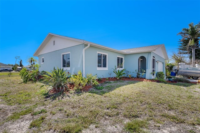 view of front of property with an attached garage, a front lawn, and stucco siding